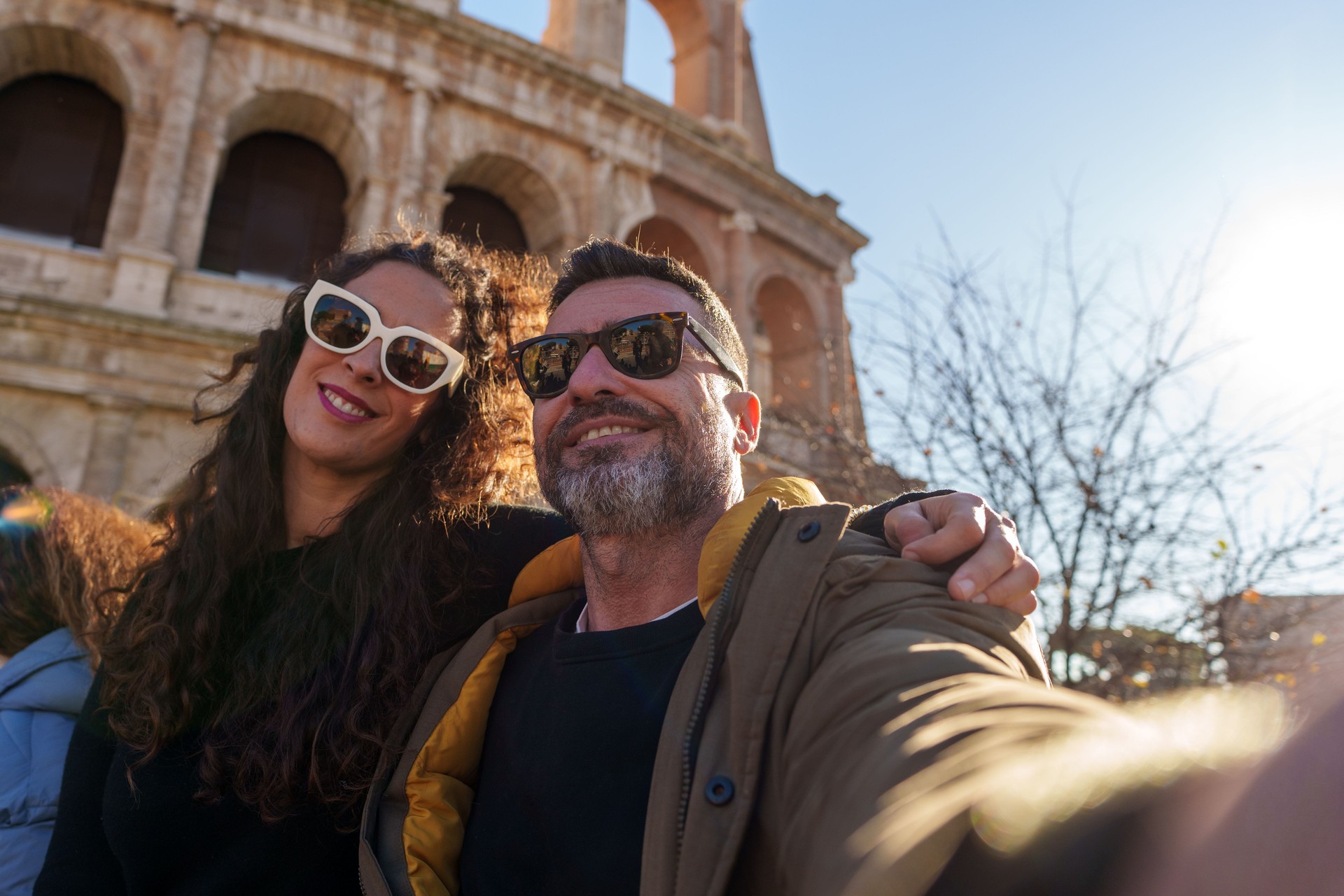 Happy mature tourists taking a selfie with the Colosseum in the background, enjoying their vacation in Rome
